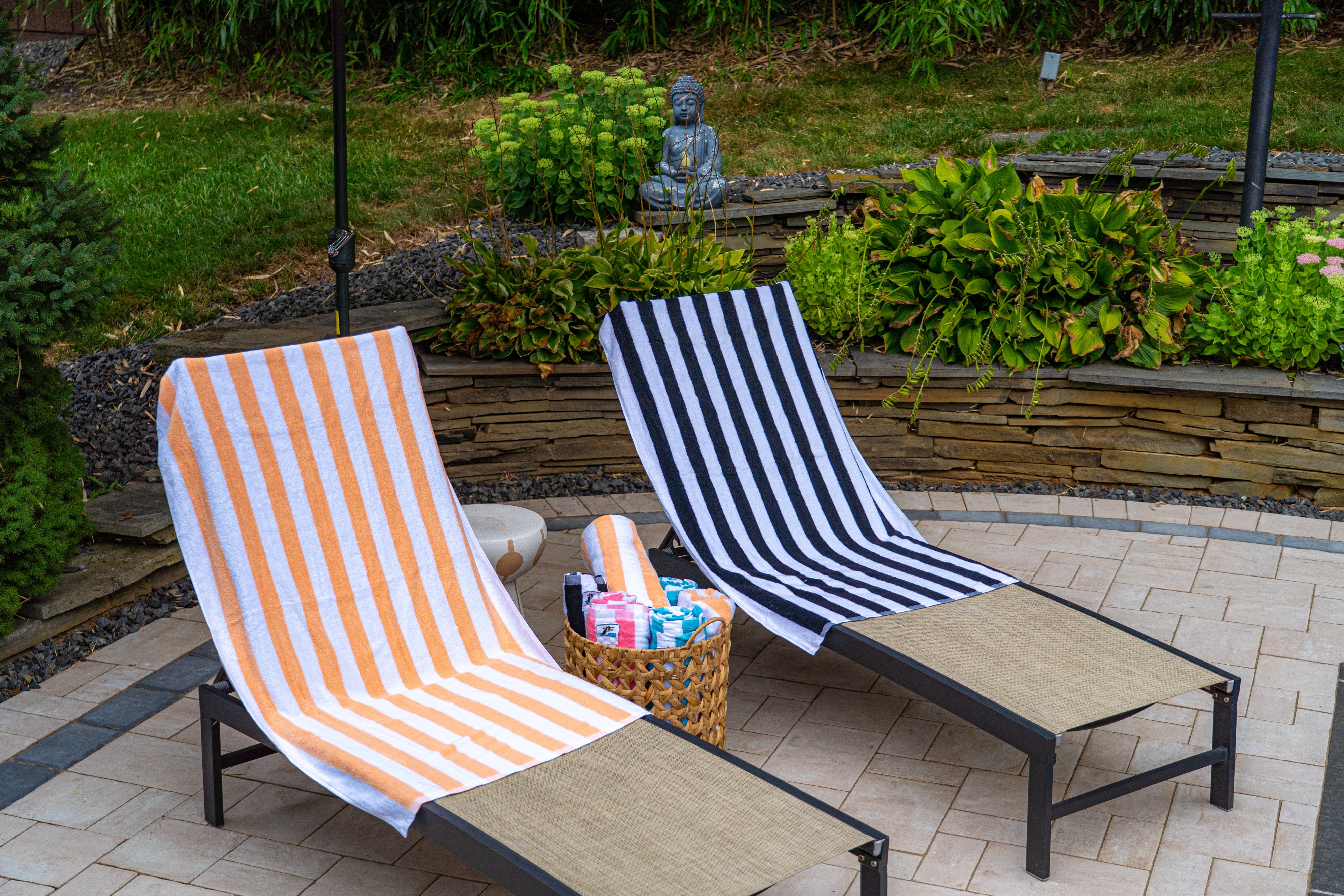Two lounge chairs with striped covers on a patio area with plants in the background